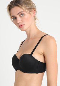 Reggiseno push-up nero modellato con spalline regolabili; texture liscia; supporto con ferretto; senza decorazioni o motivi.