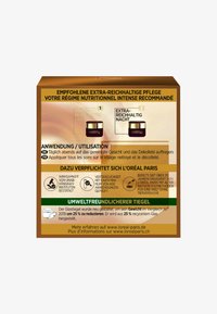 Brun låda med guldaccenter som har text på tyska och franska. Innehåller etiketter för "Extremt Rik Dag" och "Extremt Rik Natt" krämburkar.