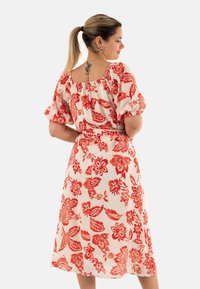 Vestido midi floral con mangas cortas abullonadas. Tela blanca con un audaz patrón floral rojo. Escote elástico y detalle de cintura entallada.