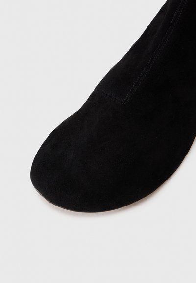Mustad suede saapad ümarate varvastega, sujuva tekstuuriga ning külje kaudu tõmmatava luku detailiga, mis muudab jalga panemise lihtsaks. Minimalistlik disain.