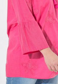 R roze tuniek met bloemenborduursels, 3/4 mouwen en een relaxte pasvorm. Lichte katoenstof met een soepele textuur.