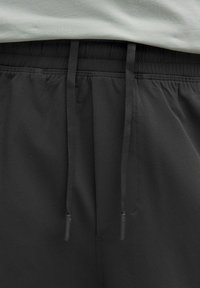 Sorte sportshorts med elastisk talje og snor. Lavet af glat materiale med sidelommer og et strømlinet design.