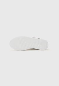 Witte sneaker met een gestructureerde rubberen zool en een bovenwerk van bruin suède. Beschikt over een geribd patroon op de zool voor grip en stabiliteit.