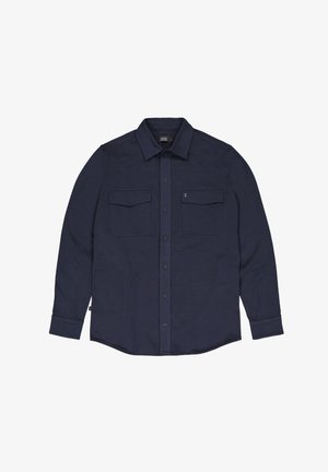Navyblauwe langarmshirt gemaakt van zacht materiaal, met twee borstzakken, knoopsluiting en een puntkraag.