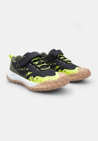 Baskets avec une tige noire, accents jaune fluo, détails verts, semelle en caoutchouc texturé et bandes Velcro pour un ajustement sécurisé.