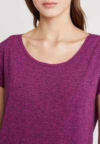 Lila kortärmad T-shirt med rundad halsringning, tillverkad av något texturerad tyg, med ett färgblandat mönster.