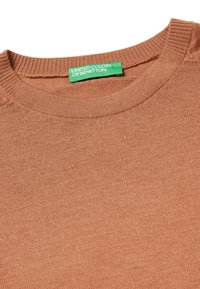 Svetr v rezavé barvě s kulatým výstřihem a žebrovanými okraji. Měkká pletená textura. Štítek nese nápis "United Colors of Benetton" v zelené barvě.