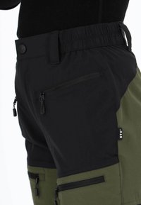 Czarno-zielone spodenki z elastycznym pasem, zamykanymi na zamek kieszeniami i metką z napisem "STX". Wykonane z lekkiego, teksturowanego materiału.