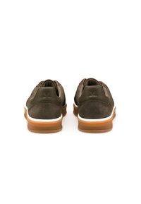 Brązowe zamszowe tenisówki z gładkim skórzanym akcentem, białą śródstopką i gumową podeszwą. Widok z tyłu pokazuje minimalne oznaczenia marki i elegancki design.