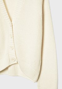 Cardigan tricoté couleur crème avec col en V, poignets côtelés et quatre boutons sur le devant.