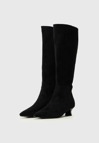 Botas de ante negras hasta la rodilla con punta afilada y tacones bajos. Textura suave y diseño minimalista, sin hardware ni adornos visibles.