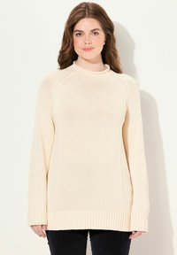 Maglione lavorato a maglia beige chiaro con orlo a coste, maniche lunghe e scollatura tonda. Presenta un motivo testurizzato e una vestibilità rilassata.