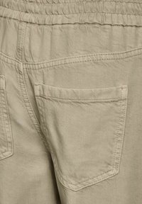 Pantalones de algodón beige con cintura elástica y dos bolsillos traseros con un patrón de costura simple. Textura suave, diseño de corte recto.