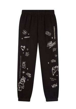 Pantaloni della tuta neri con scarabocchi e testo bianco, tra cui cuori, ciliegie, un coniglio, dadi, ali d'angelo e frasi come "La magia accade" e "Andrà tutto bene".