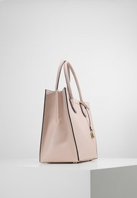 Rosa läderhandväska med strukturerad design, svart kantning, två handtag och ett litet guld- låsdetalj framtill. Texturerad yta.