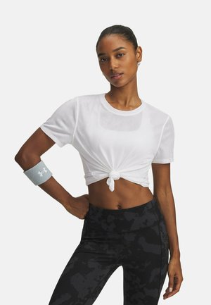 Cropped top in rete bianca con dettaglio anteriore annodato, indossato con leggings neri a vita alta con motivo; accessoriato con un braccialetto grigio.