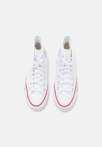 White high-top sneakers made of canvas, featuring a classic design with red accents, white rubber sole, and traditional lace-up closure.