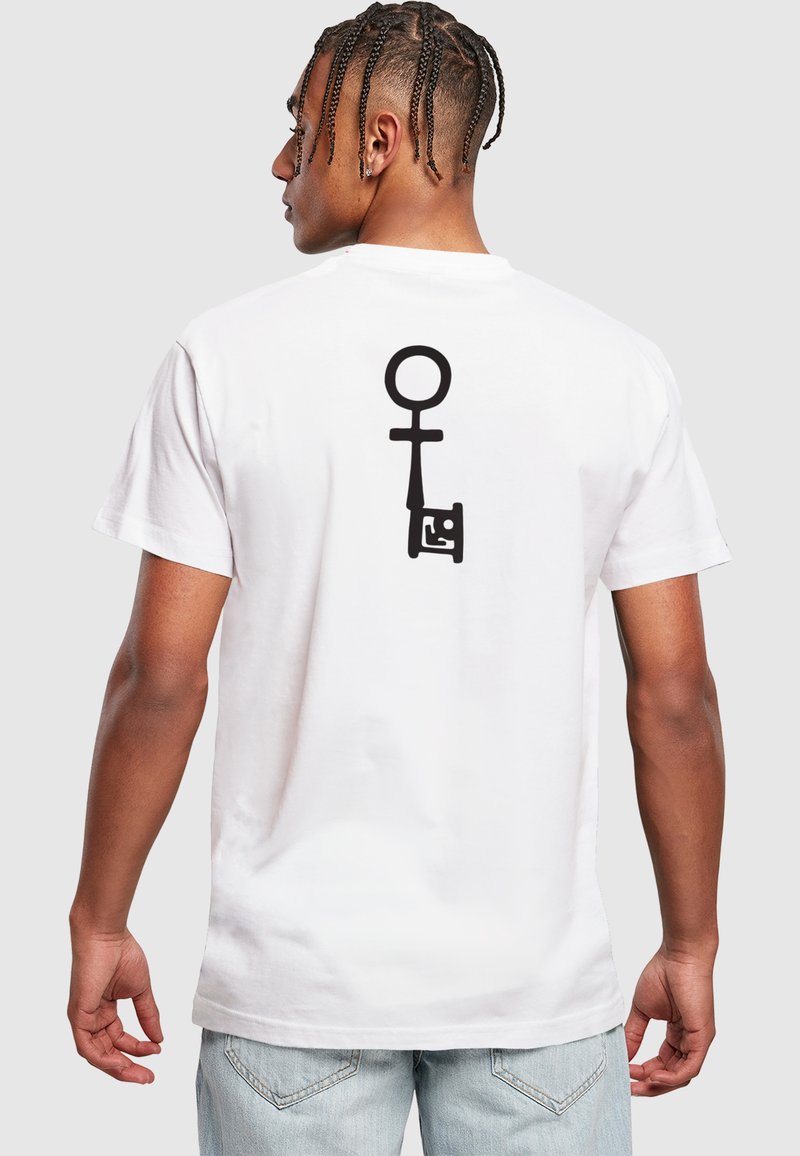 Hvid bomulds T-shirt med et stort sort grafisk design på ryggen, der ligner en nøgle og et kønssymbol. Casual pasform med korte ærmer.