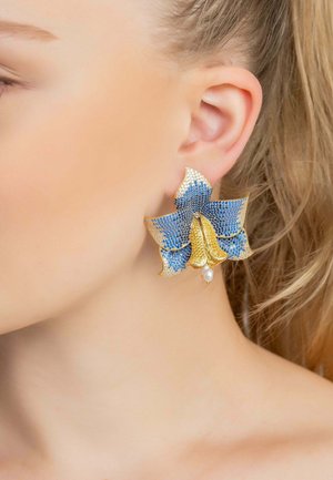 Gold and blue flower-shaped earring with rhinestone embellishments and a white pearl accent, showcasing intricate design and vibrant colors.
