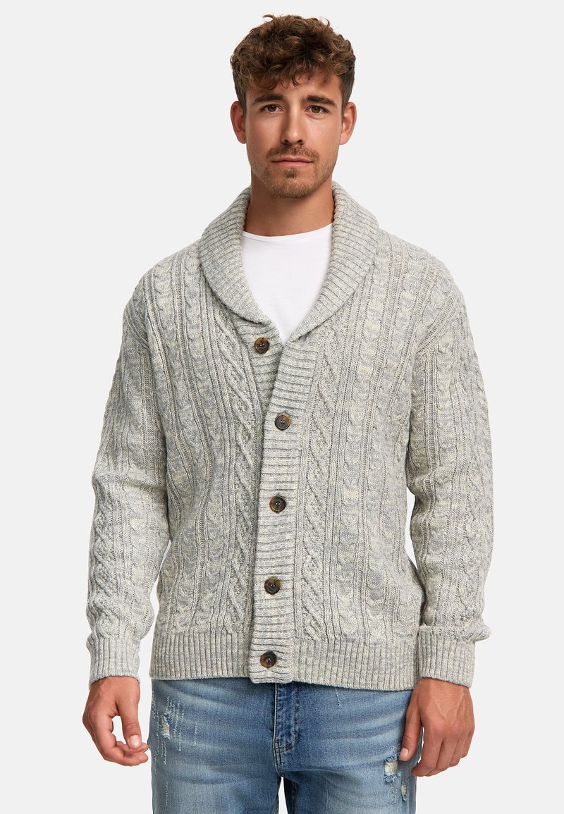 Valkoknitted cardigan vaaleanharmaana, jossa on huivikaulus, viisi ruskeaa nappia sekä ribatut hihansuut ja helma. Farkut, joissa on kulutettuja yksityiskohtia.