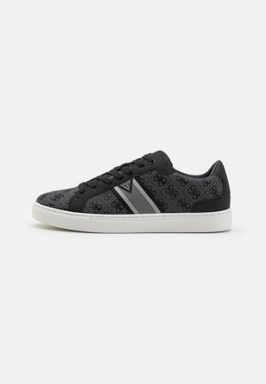 Sneaker nero e grigio con una tomaia testurizzata caratterizzata da un motivo embossato, lacci piatti e strisce grigie a contrasto, montata su una suola bianca.