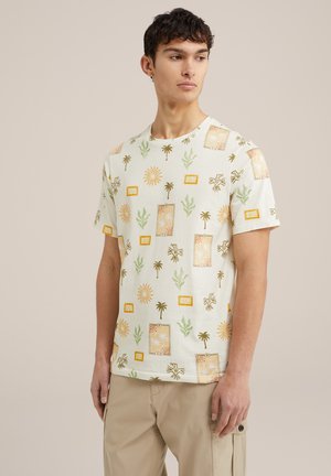 Lyhythihainen, vaalean vihreä puuvillapaita, jossa on kuviollinen design, joka sisältää auringon, palmupuita ja kehystettyjä kasvi-motiiveja keltaisena ja vihreänä.