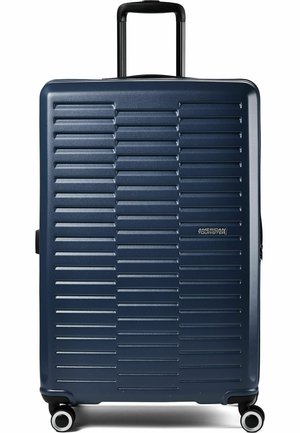Dunkelblauer Hartschalenkoffer mit horizontalen Rillen, vier Spinner-Rädern, ausziehbarem schwarzem Griff und American Tourister Logo vorne.
