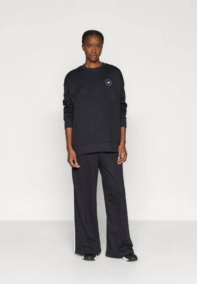 Μαύρο φούτερ και παντελόνι με φαρδιά μπάσκα από απαλό ύφασμα. Το φούτερ διαθέτει στρογγυλό λογότυπο στο στήθος.