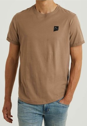 T-shirt di cotone marrone con maniche arrotolate. Presenta una piccola toppa nera con logo sul petto sinistro e un design a orlo dritto.