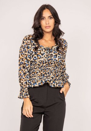 Blouse à manches longues en tissu à motifs présentant des couleurs bleu, orange et beige, avec une taille smockée et des poignets volants.