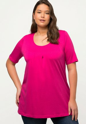 T-shirt fuchsia à manches courtes avec un décolleté dégagé, doté de deux plis sous la poitrine et d'une texture de tissu lisse.