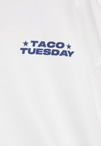 Biały materiał z ciemnoniebieskim napisem „TACO TUESDAY” umieszczonym na środku między dwoma gwiazdami.