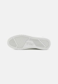Soletta di sneaker in gomma bianca con un motivo testurizzato per grip, con un logo centrato nella zona del battistrada. Superficie complessivamente liscia.