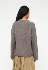 Gray knitted sweater with a ribbed hem and collar. Relaxed fit, dropped shoulders, and a seamless back design.