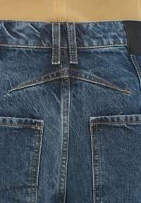 Τζιν παντελόνια με ξεθωριασμένο μπλε φινίρισμα, με αντίθετη πορτοκαλί ραφή, ψηλή μέση και δύο πίσω τσέπες. Ζώνη μέσης με ραβδώσεις και υφή.