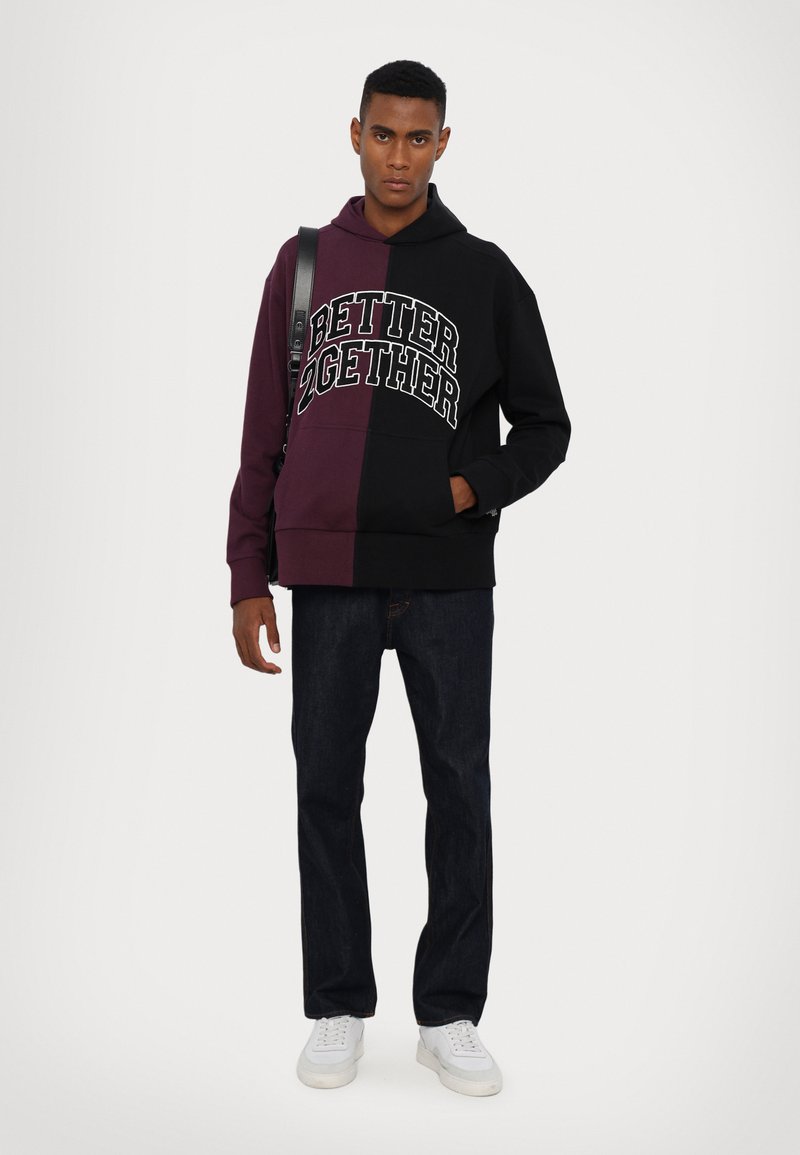 Black and burgundy color-blocked hoodie with the text "BETTER 2GETHER," paired with dark jeans and white sneakers.