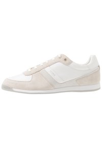 Nízkoprofilová bílá a béžová semišová teniska s síťovými panely a tkaničkami, v minimalistickém designu a s nenápadným logem na boku.