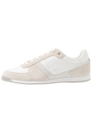 Niedrigprofilierter, weißer und beiger Wildledersneaker mit Mesh-Einsätzen und Schnürsenkeln, der ein minimalistisches Design und dezente Markenkennzeichnung an der Seite aufweist.