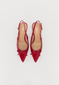 Tacchi slingback rossi in vernice con punte affusolate, dotati di un dettaglio a fiocco sul davanti e di una sottile tracolla con fibbia dorata.