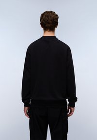 Sort sweatshirt med langeærmer, rund halsudskæring, blød tekstur og ribbede manchetter samt kant. Båret sammen med matchende sorte cargo-bukser.