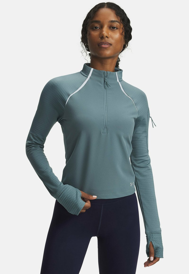 Teal athletic pullover with half-zip, collar, and long sleeves. Textured sleeve cuffs and reflective accents enhance visibility and style.