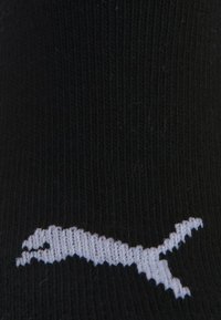 Black fabric with a white knitted logo of a leaping puma or mountain lion near the bottom center.