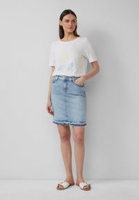 Witte T-shirt met korte mouwen met de opdruk "LEISURE CLUB", gecombineerd met een lichtdenim kokerrok met rafelige zoom en zakken. Witte sandalen.