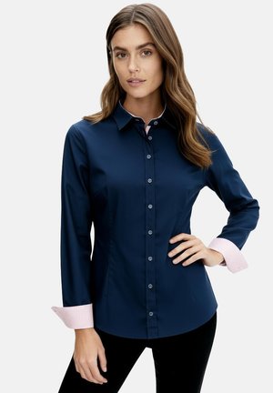 Navy blue button-up shirt with a fitted design. Features contrasting light pink striped cuffs and a classic collar with button detail.