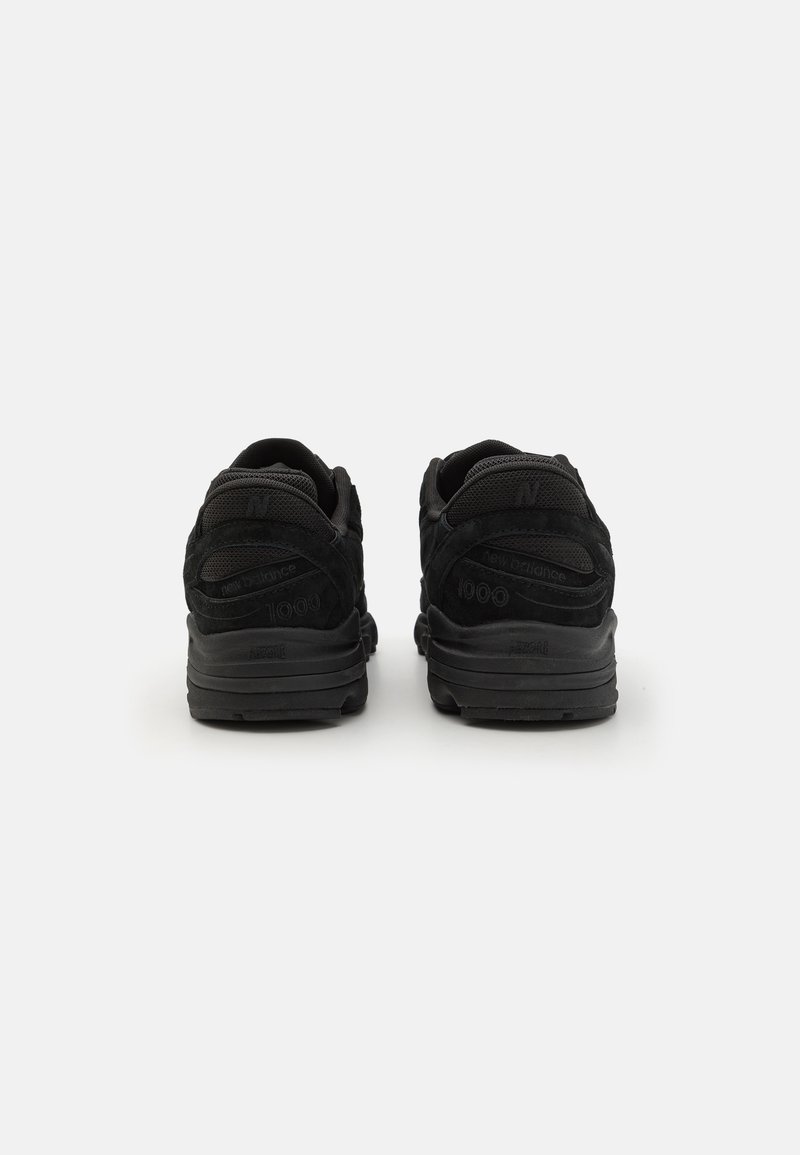 Las zapatillas deportivas negras cuentan con una parte superior de ante y malla, un collar acolchado, acentos de logotipo notables y una suela de goma texturizada.