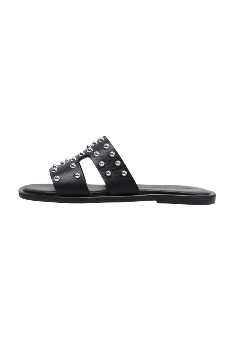 Chanclas negras de slide con dos tiras anchas adornadas con tachuelas plateadas. Suela plana, hecha de material suave, diseño minimalista.