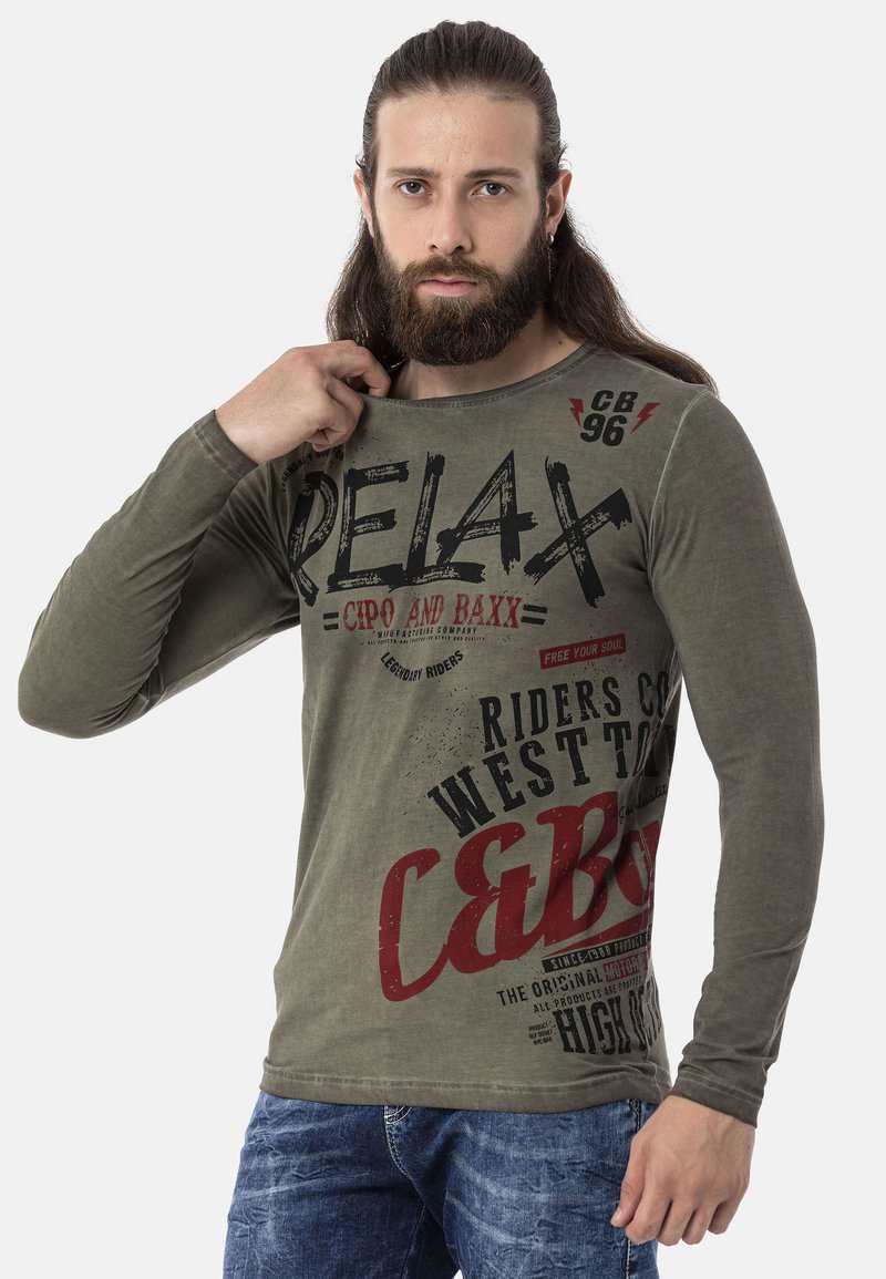 Langärmliges olivgrünes Hemd mit fettem Text und Grafiken in Schwarz und Rot, mit rundem Ausschnitt und weichem Material.
