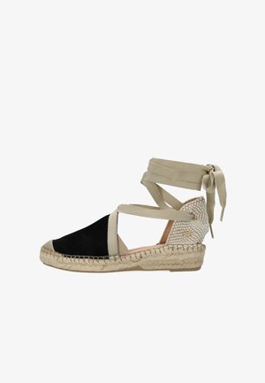 Zwarte suède espadrille sleehak met beige canvas enkelbandjes en een gevlochten jutezool, voorzien van een getextureerde hakdetail en ronde accenten.