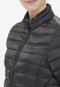Svart pufferjacka med hög krage, med quiltat mönster och dragkedja framtill. Logotypen "WHISTLER" är tryckt i grått på bröstet.