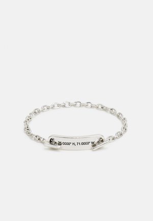 Pulseira de prata com um design de corrente e uma placa curva inscrita com as coordenadas "25.0000° N, 71.0000° W." Acabamento em metal suave.
